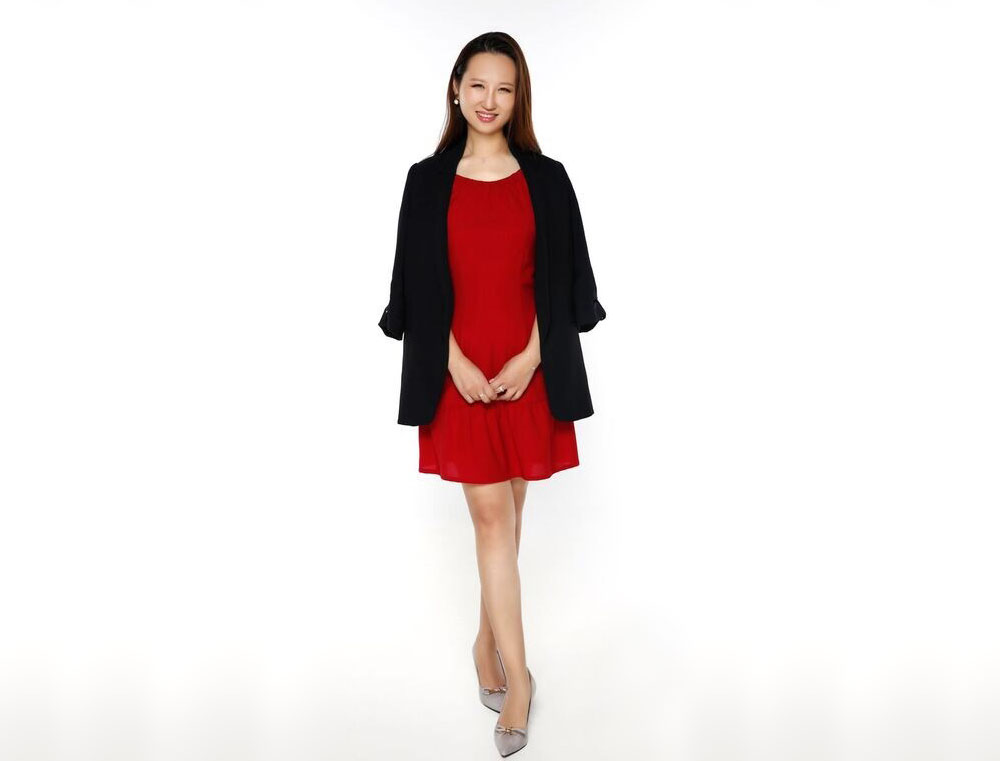 Angela Jing Yang in a red dress with a jacket over her shoulders.