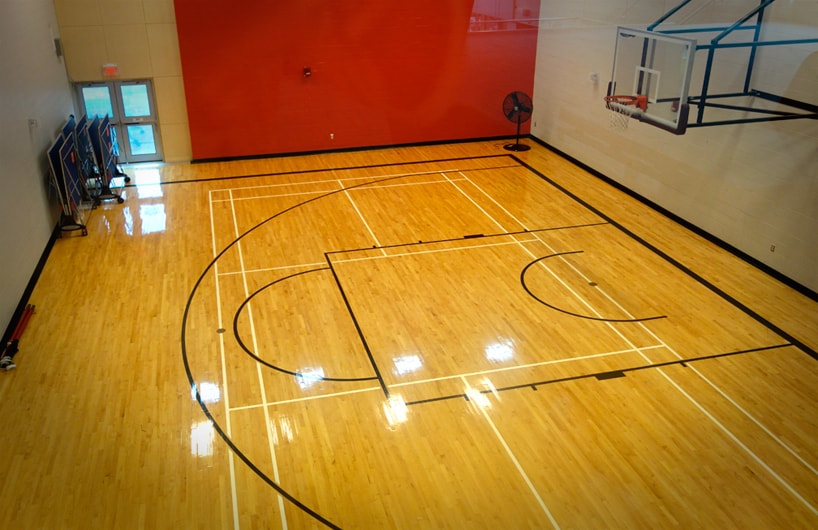 View of the community room from above looking down at hardwood floor and basketball net.