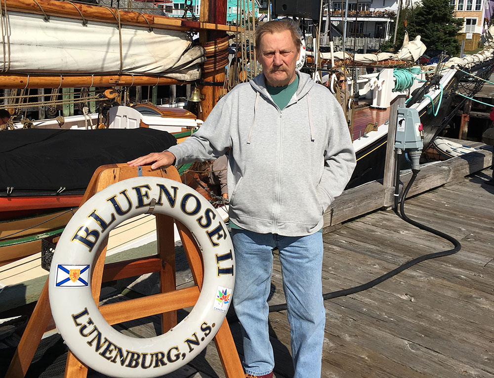 David Norton standing beside a Bluenose II life preserver.