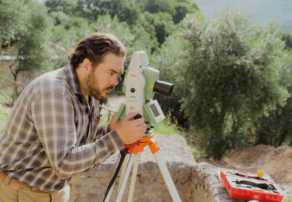 A man uses surveying equipment outdoors at the Villa di Tito archaelogical site