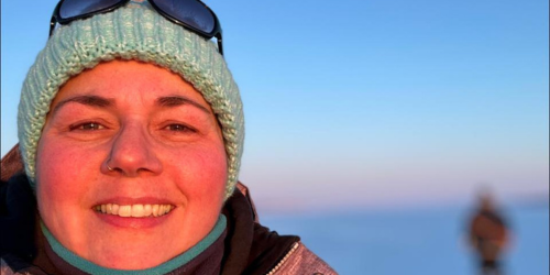 Jodie wears a hat and winder jacket and stands outdoors in a wintery northern landscape
