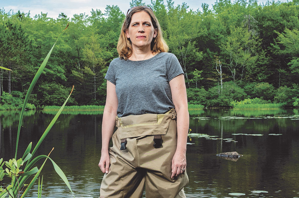 A person in waders stands in water.