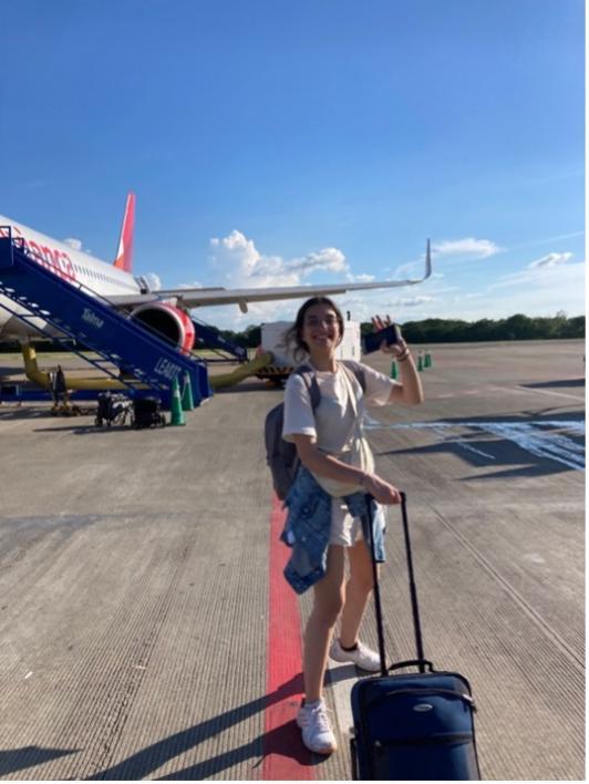 A student with a luggage about to enter in a airplane