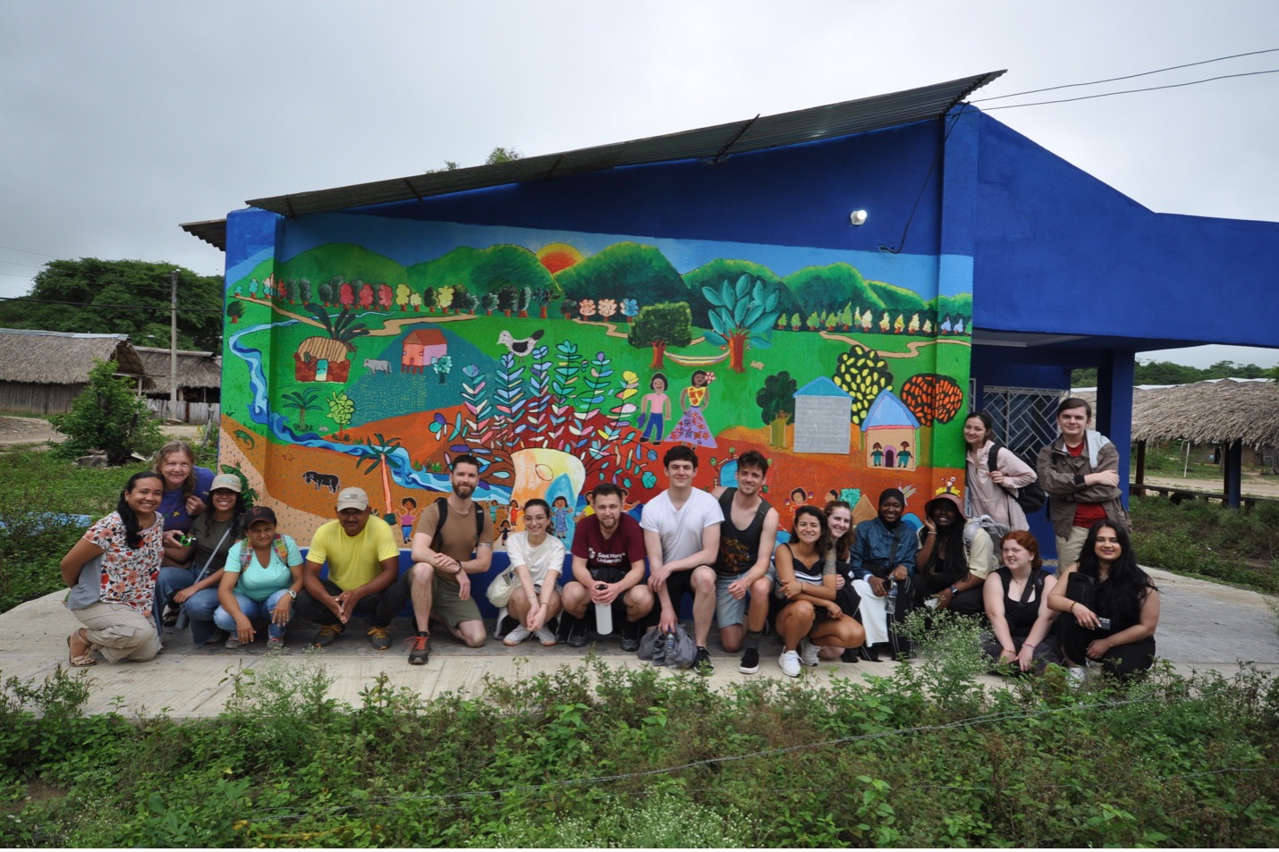 A group of students posing on a graffiti wall in a community in Colombia