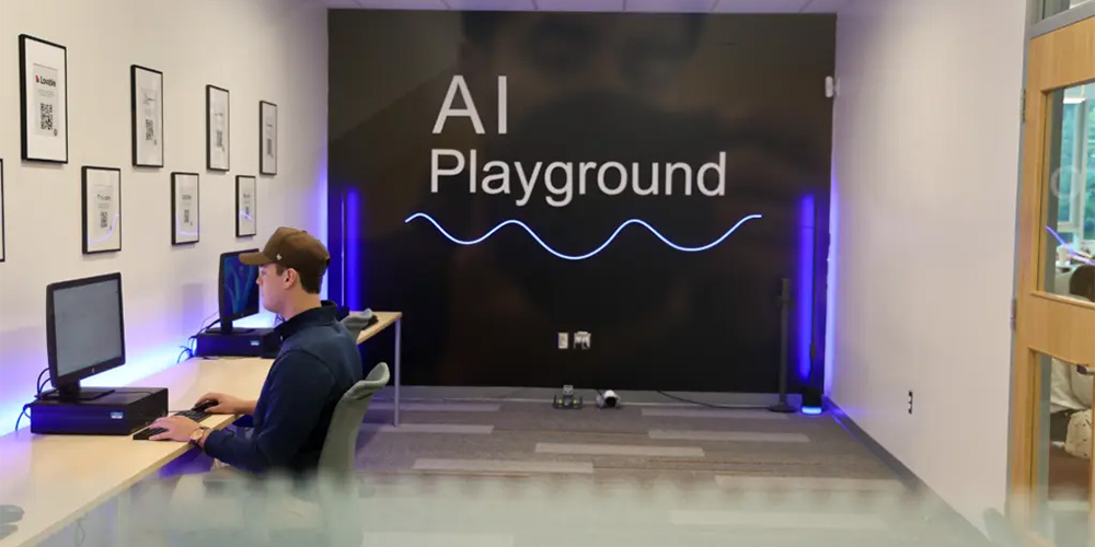 A student sits at a desk with an AI Playground sign behind him.