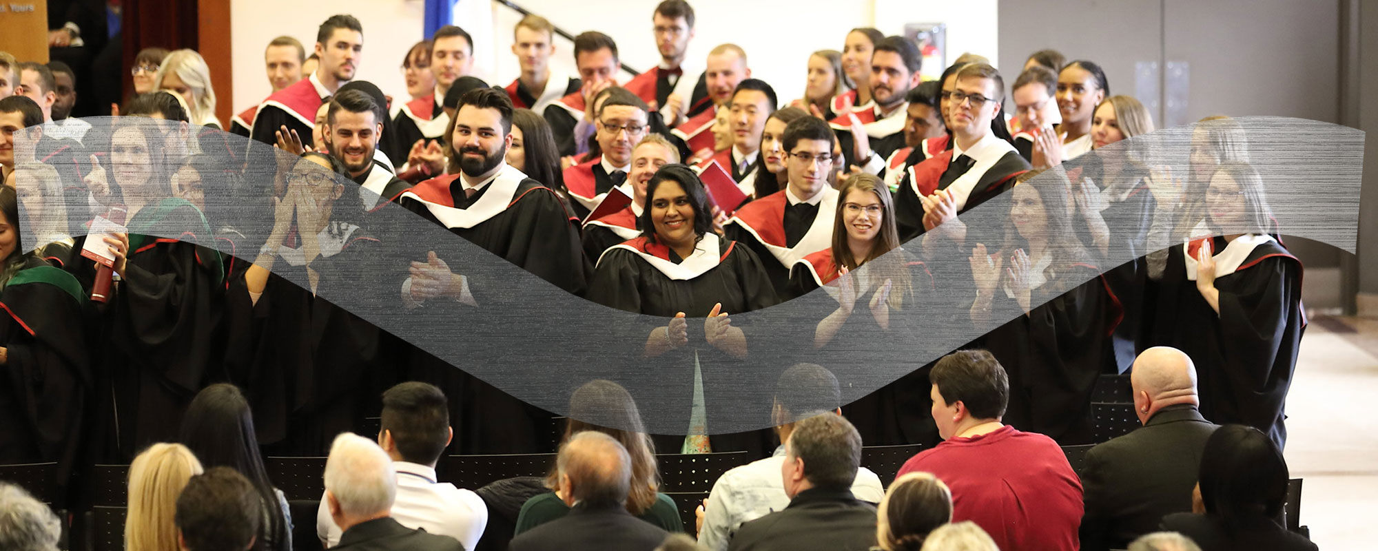 Graduates in gowns applauding each other.