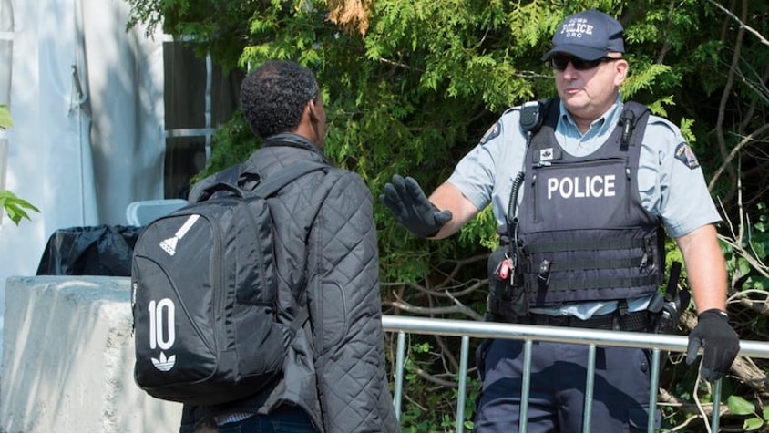 An asylum seeker is confronted by an RCMP officer as he crosses the border into Canada in 2017