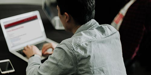 A young man looking at a Saint Mary's webpage on a laptop.