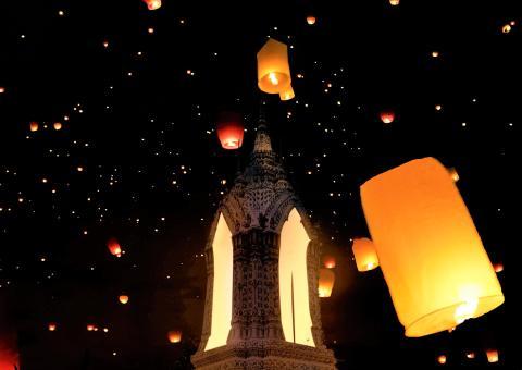 Photograph of paper lanterns floating up into the night sky at the Thai Lantern Festival