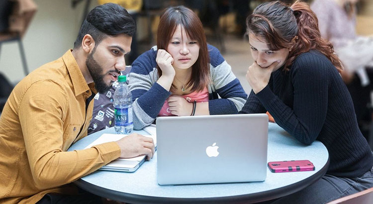 Three students looking at a laptop screen