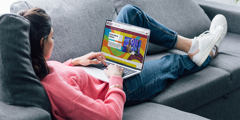 Student lying on couch looking at Future Students site.