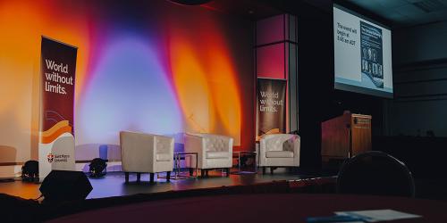 Four empty chairs on a dramatically lit stage.