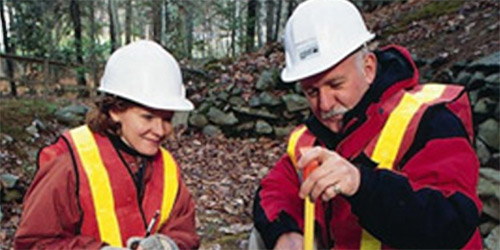 Two people in hard hats taking depth measurements.
